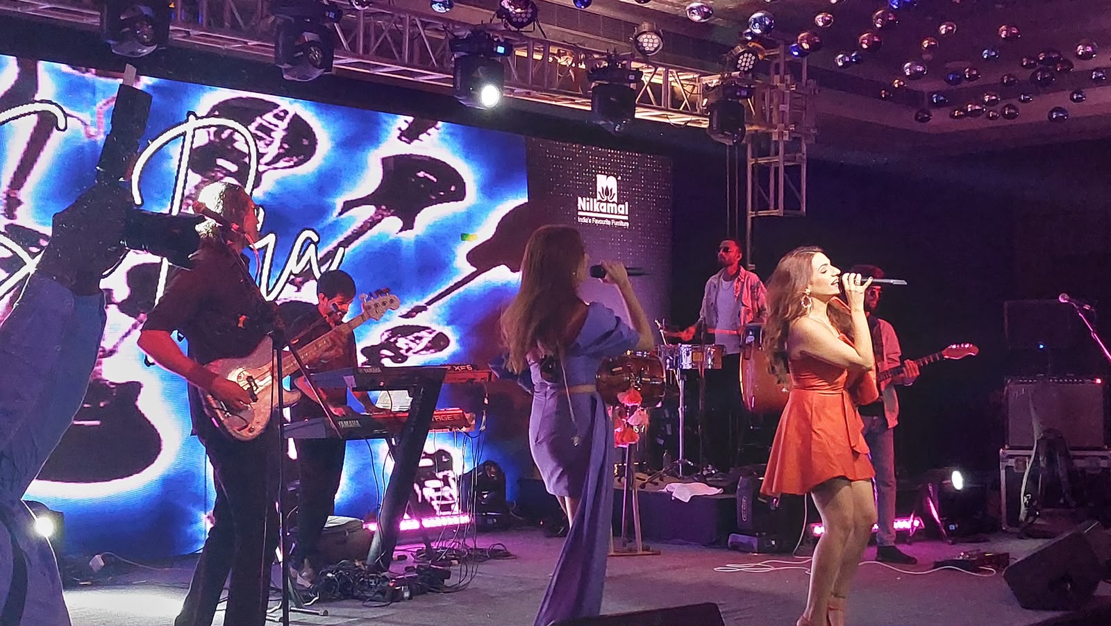Live band performing at Nilkamal event with vocalists, guitarists and LED backdrop