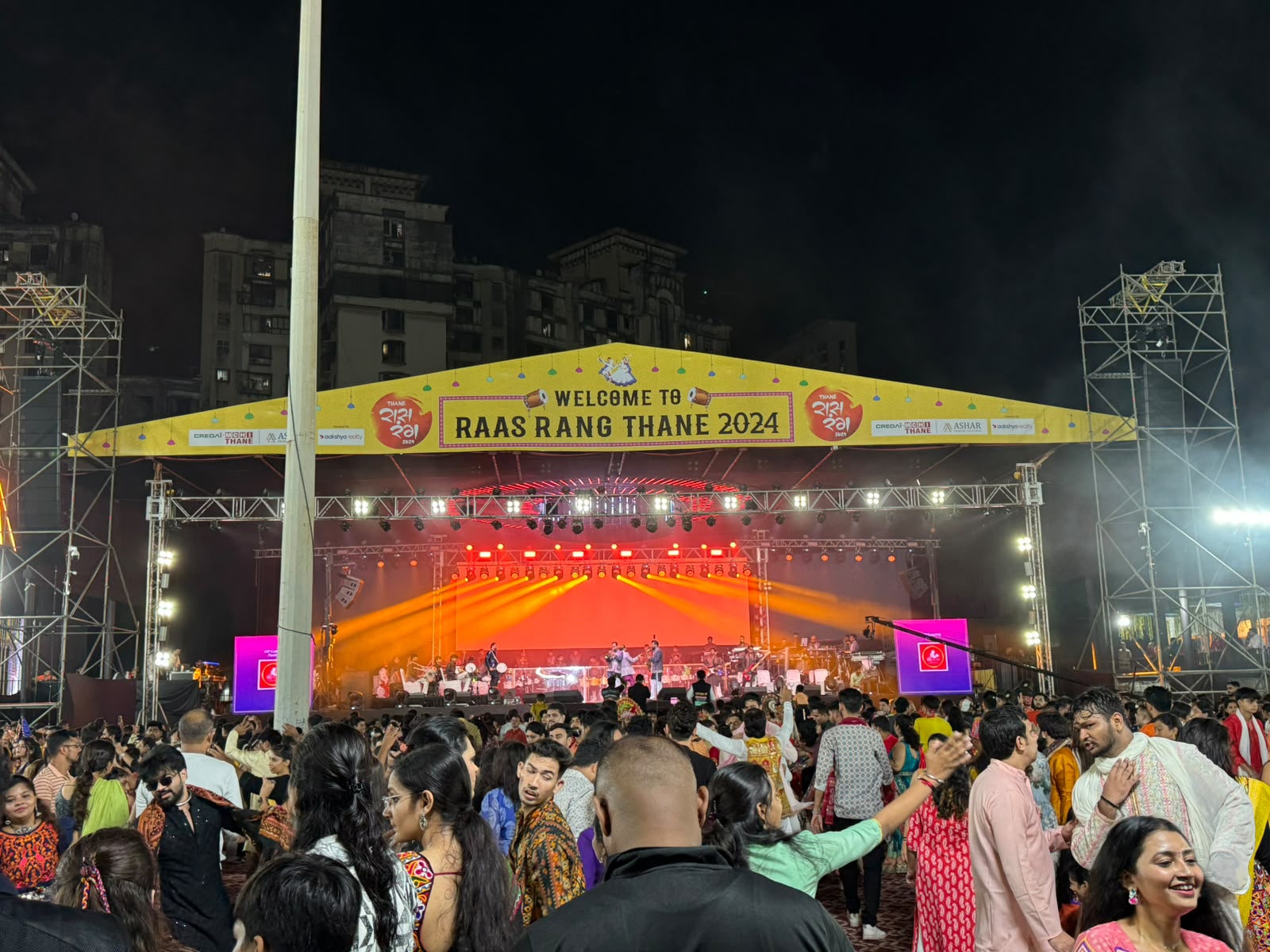 Raas Rang Thane 2024 Garba night stage with orange beam lighting and dancing crowd in traditional attire