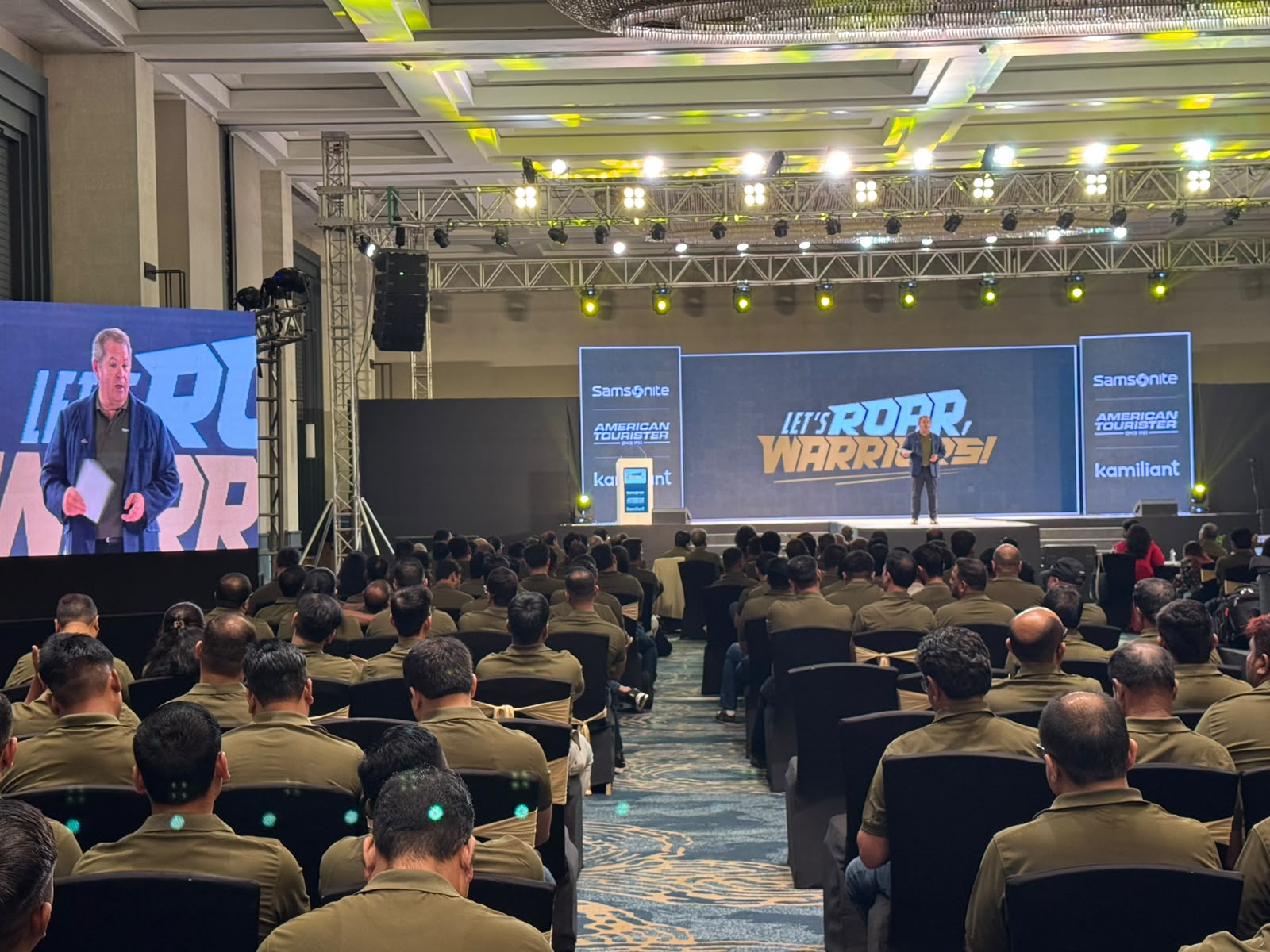 Samsonite Let's Roar Warriors conference stage with American Tourister and Kamiliant branding and seated audience