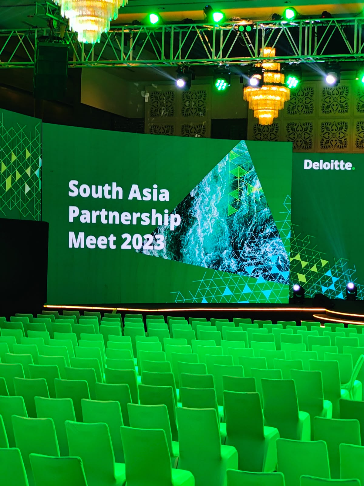 Deloitte South Asia Partnership Meet 2023 stage with green lighting and chandeliers