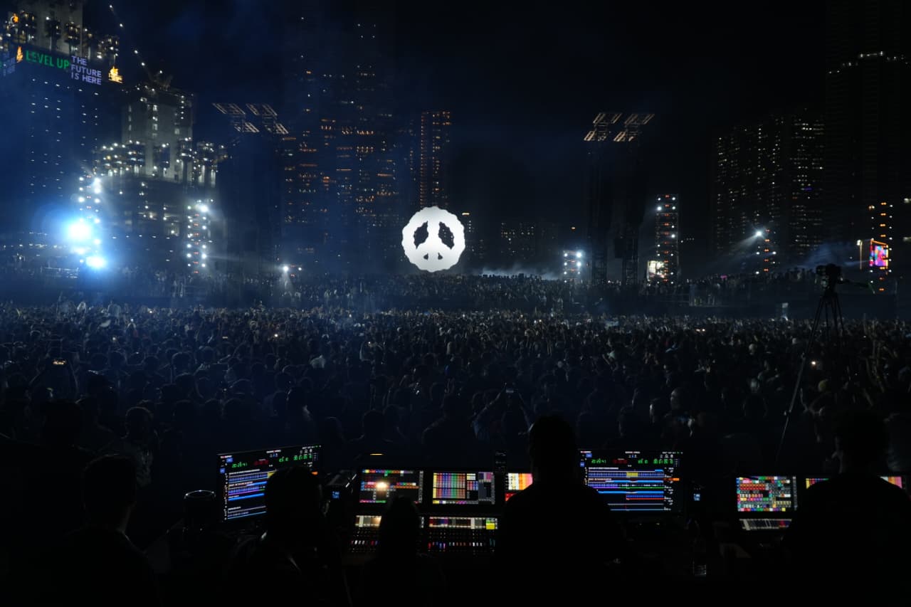 Keinemusik main stage at night with illuminated peace sign and massive crowd in front of Mumbai skyline