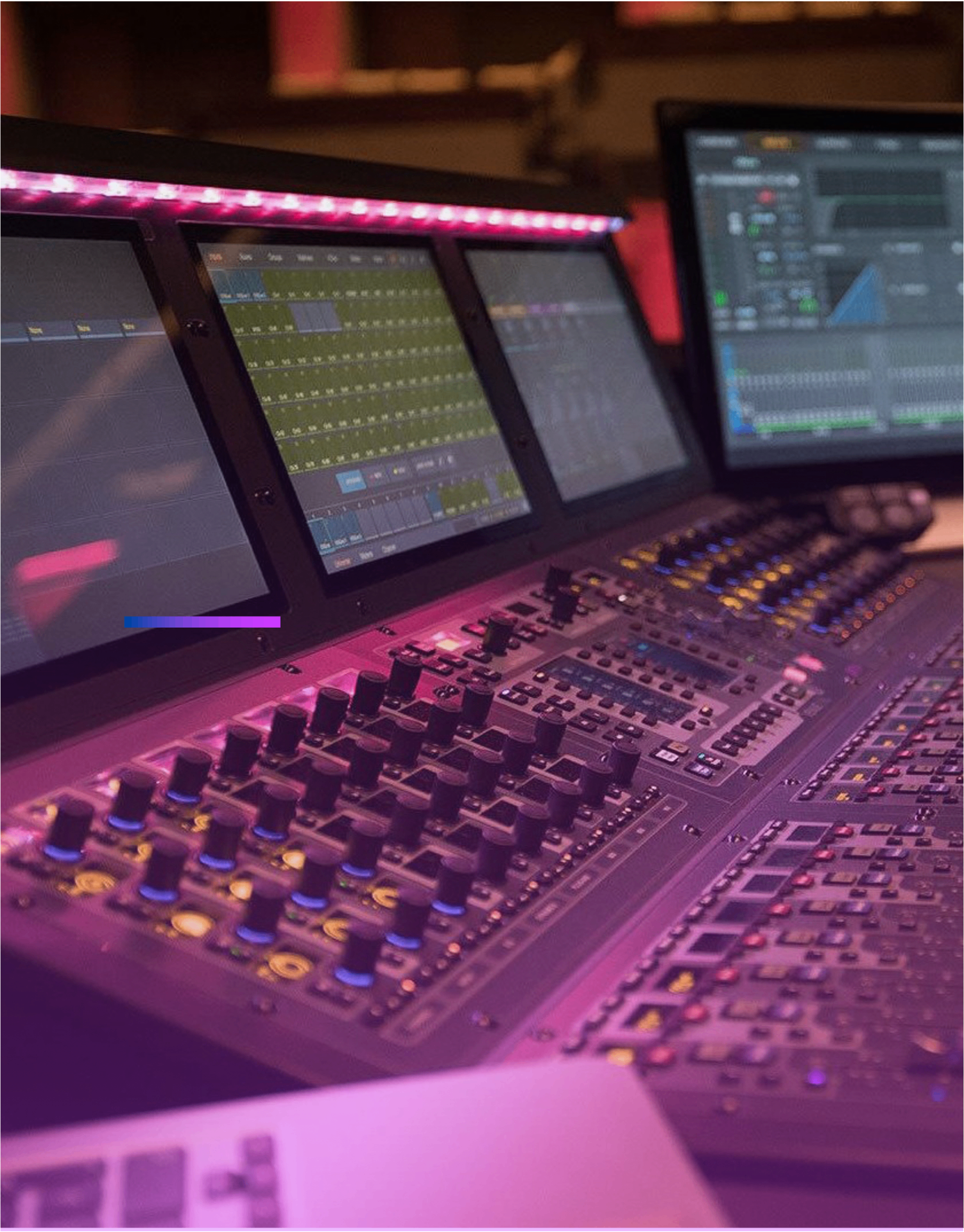 Close-up of Avid S6L mixing console with multiple screens and rotary encoders under studio lighting